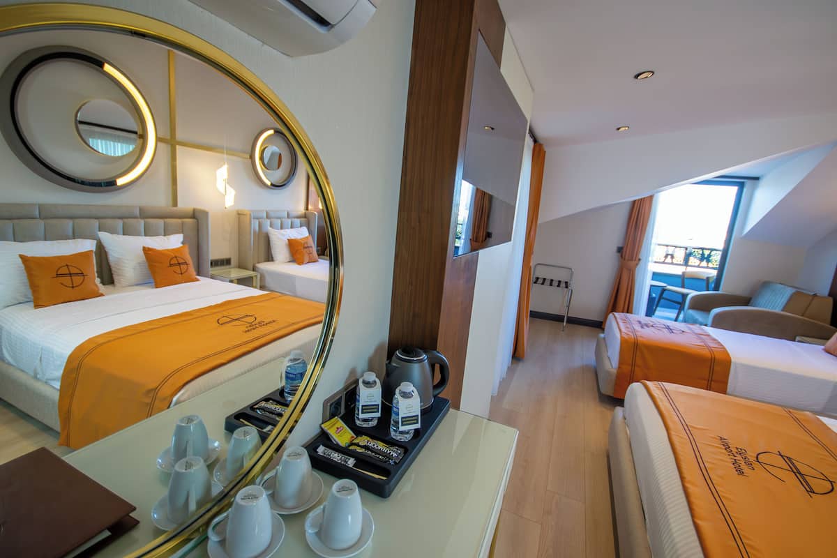 Habitación de hotel con dos camas, un espejo grande, una zona de café y vistas al exterior.