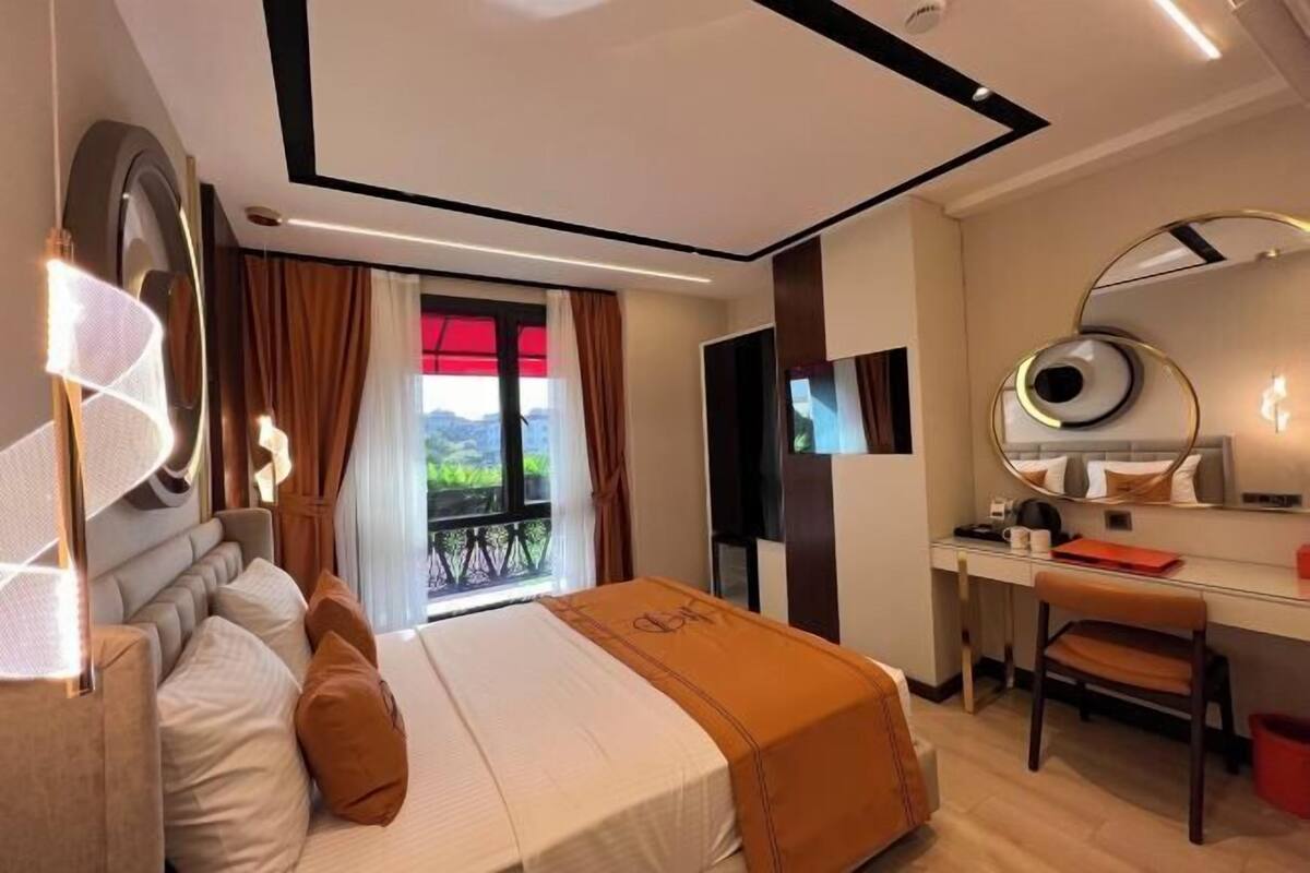 Habitación de hotel con cama, escritorio, silla, televisor y vistas al exterior.