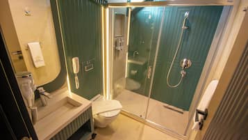 Un baño con ducha de vidrio, lavabo e inodoro.