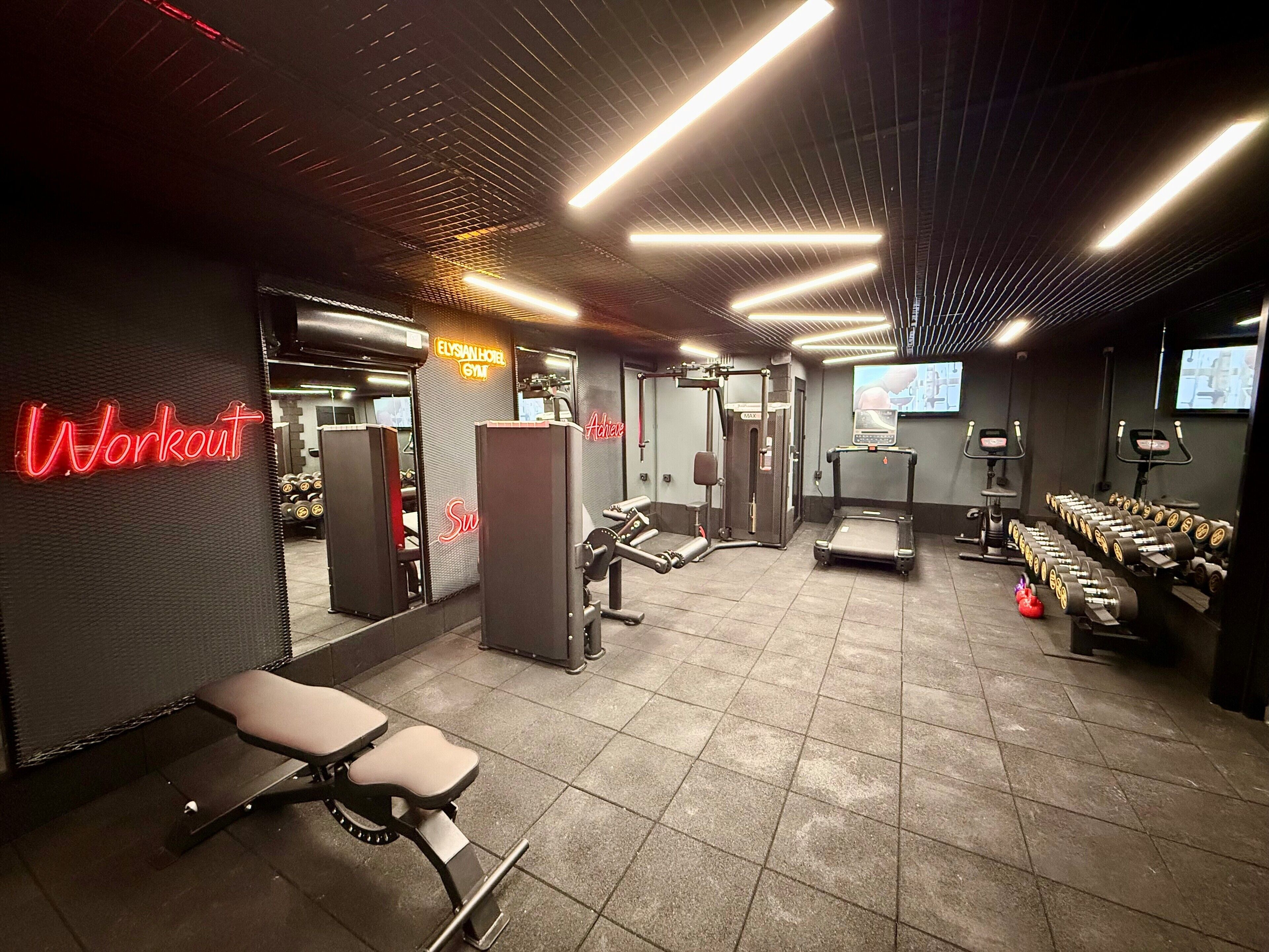 Een fitnessruimte met trainingsapparatuur, een loopband en gewichten.