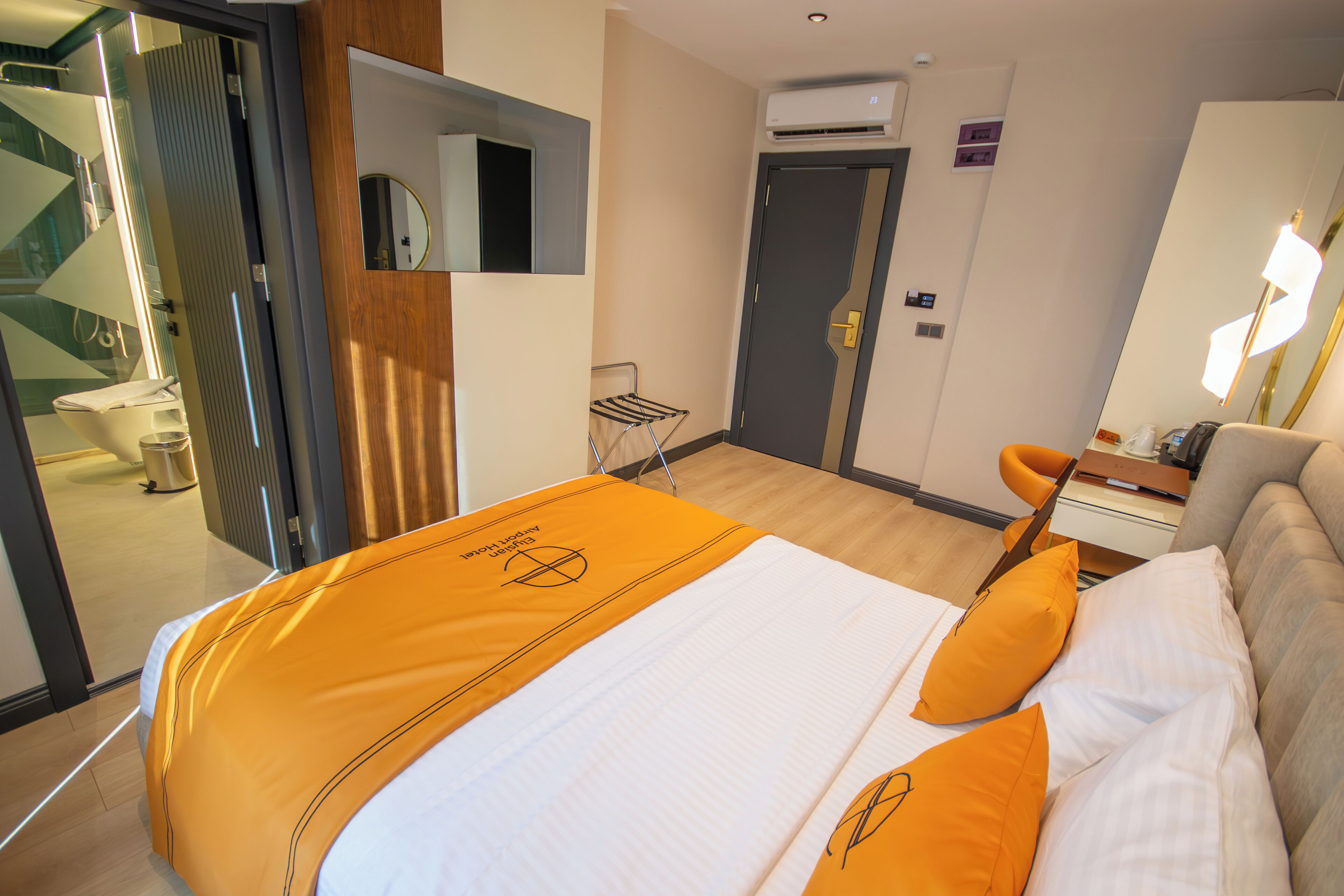 Een hotelkamer met een bed, een bureau, een stoel en een badkamer zichtbaar door een geopende deur.