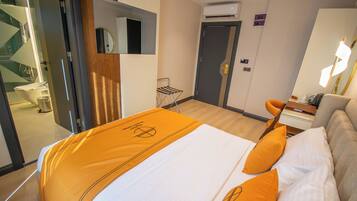 Een hotelkamer met een bed, een bureau, een stoel en een badkamer zichtbaar door een geopende deur.