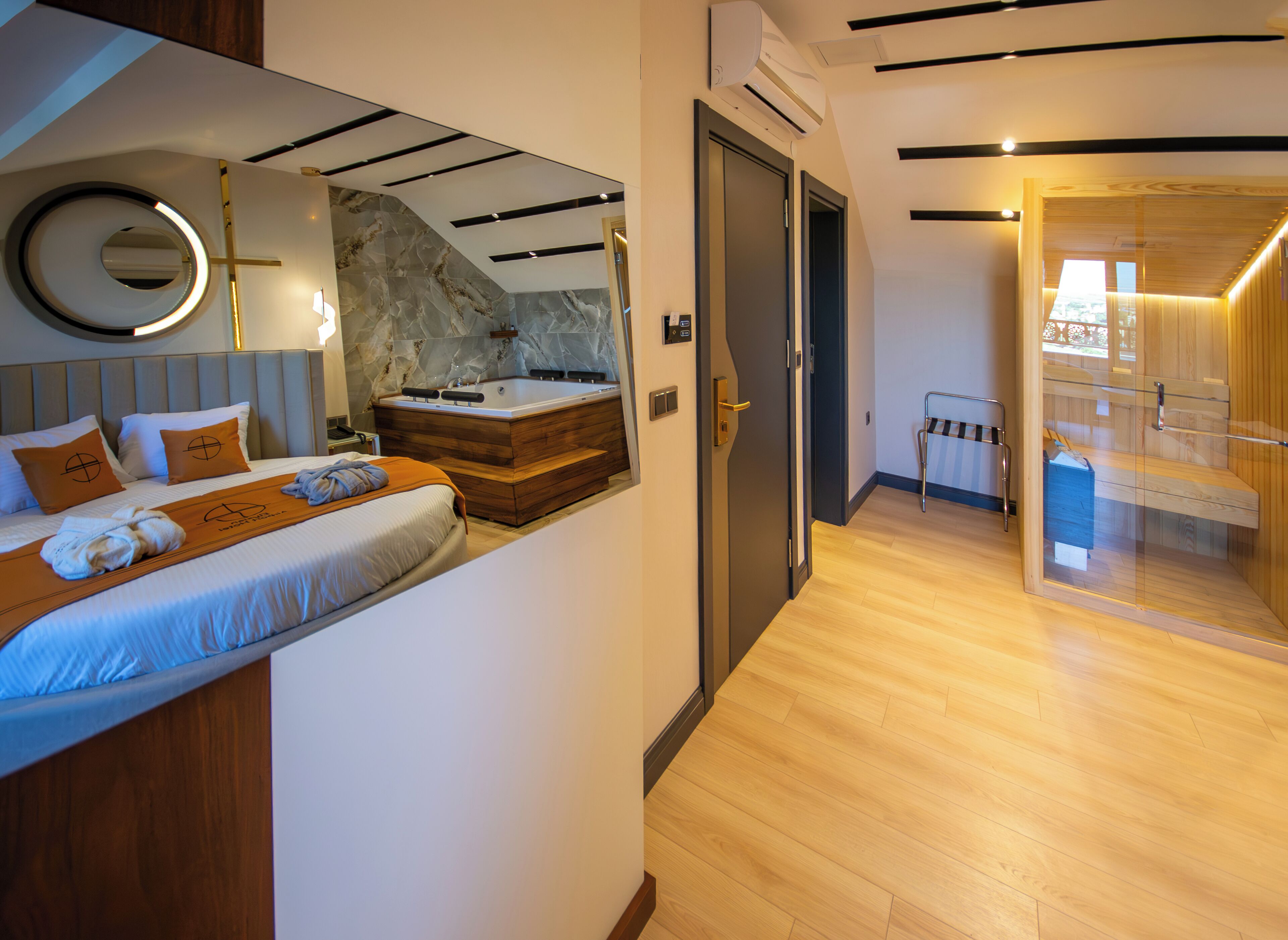 Una habitación de hotel moderna con una cama, un baño con bañera y suelo de madera.
