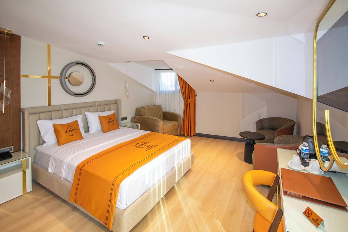 Una habitación de hotel moderna con una cama grande, un escritorio y una zona de estar.