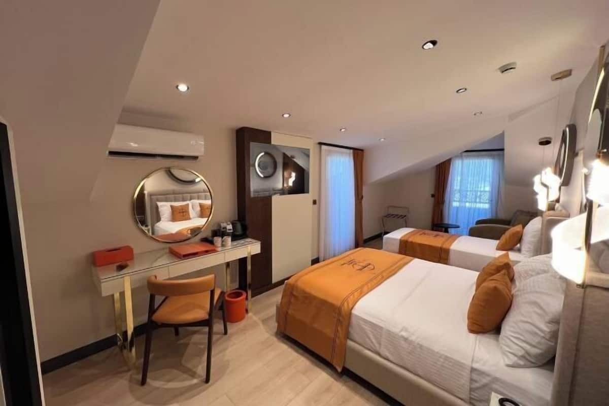 Habitación de hotel con escritorio, dos camas, un espejo y vista a la ciudad.