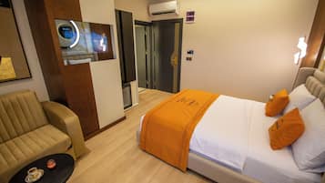 Una habitación de hotel con una cama, un sofá, una mesita y un televisor.