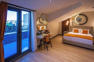 Una habitación de hotel moderna con una cama grande, un escritorio y un balcón con vista a la ciudad.