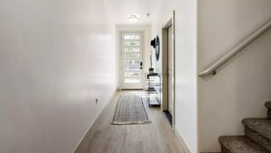 A hallway with a wooden floor, a rug, a metal shelf, and a staircase. - Sleeps 18! Pool! Pizza Oven! 2 Townhomes! (Santa Clara)