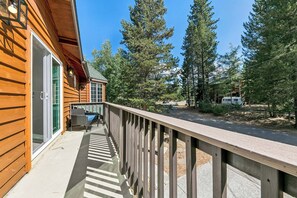 A wooden cabin with a balcony overlooking a forested area.
