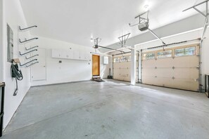 A spacious garage with two large doors, a concrete floor, and overhead lighting.