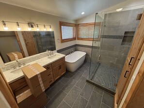 A bathroom with a double sink vanity, a freestanding bathtub, and a glass-enclosed shower area.