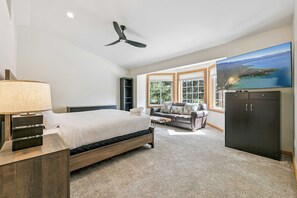 Une chambre moderne avec un lit, un bureau, une télévision et une grande fenêtre.