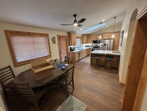 A kitchen with wooden cabinets, a dining table with chairs, a ceiling fan, and a built-in microwave.
