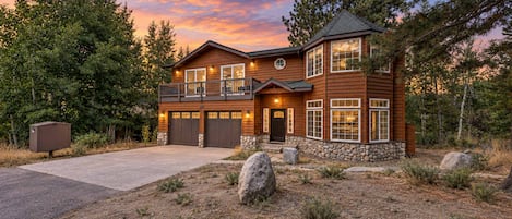A two-story wooden house with a stone foundation, a garage, and a balcony.
