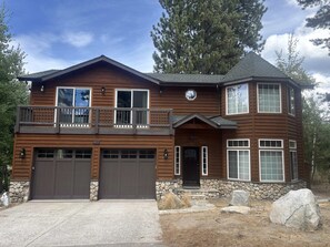 A two-story house with a stone foundation, a balcony, and a garage.