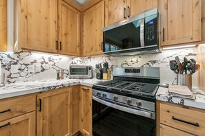 Une cuisine avec des meubles de rangement en bois, un four à micro-ondes, un grille-pain et une cuisinière.