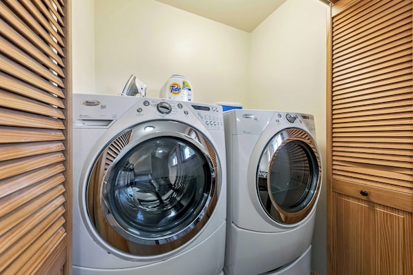 A laundry room with two front-loading Whirlpool Duet washers and a Tide detergent bottle on the counter.