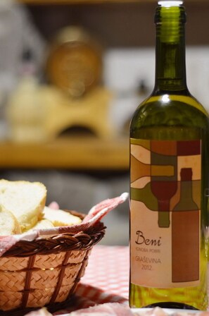 Une bouteille de vin Beni, dont l’étiquette présente un verre à vin et une bouteille, est posée sur une table, à côté d’un panier de pain.