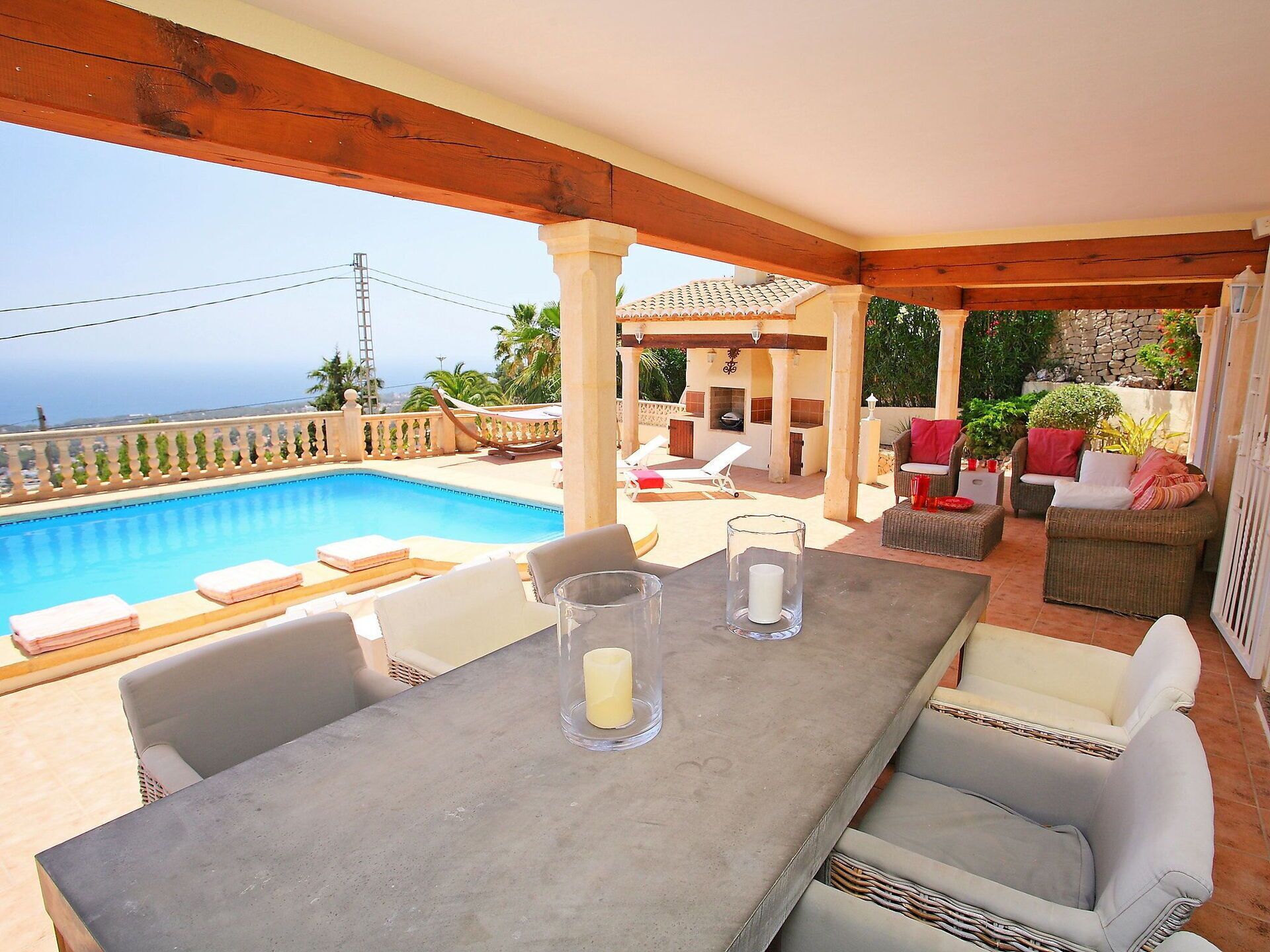 Un espacio al aire libre cubierto con piscina, sillas de descanso y una mesa con velas.
