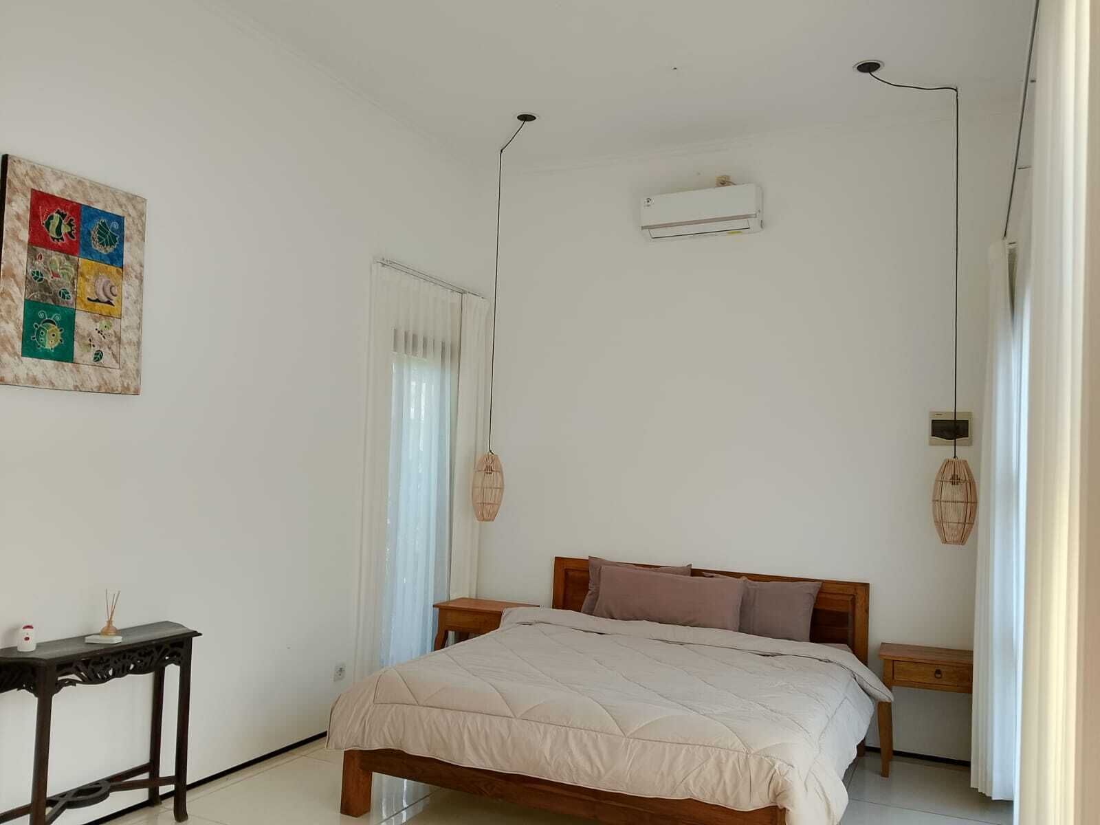 Ein Schlafzimmer mit Bett, Nachttisch, Wand-Klimaanlage und einer Wanddekoration.