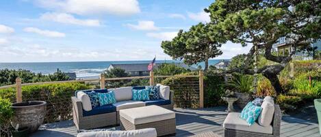 A deck with wicker furniture, a view of the ocean, and a flag.