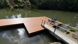 A wooden dock extending into a calm lake with a metal railing and a chair. - Spectacular Riverfront Setting, Pet Friendly, EV Charger, Fire-Table, Sauna, BBQ Overlooking River (West Linn)
