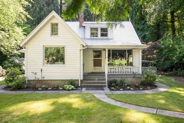 Une maison de plain-pied avec un porche à l’avant, un petit garage attenant et un jardin bien entretenu.