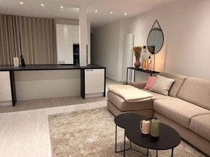 A modern living room with a sofa, a coffee table, a desk, and a mirror.