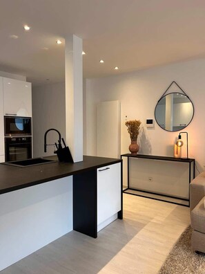 A modern kitchen with a central island, built-in oven, and a round mirror on the wall.