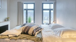 Une chambre avec deux lits, une cheminée et de grandes fenêtres.