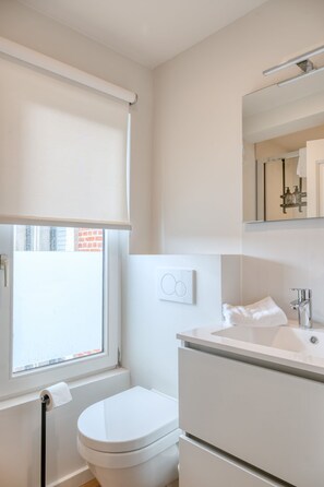 Ein modernes Badezimmer mit Toilette, Waschbecken und Spiegel.