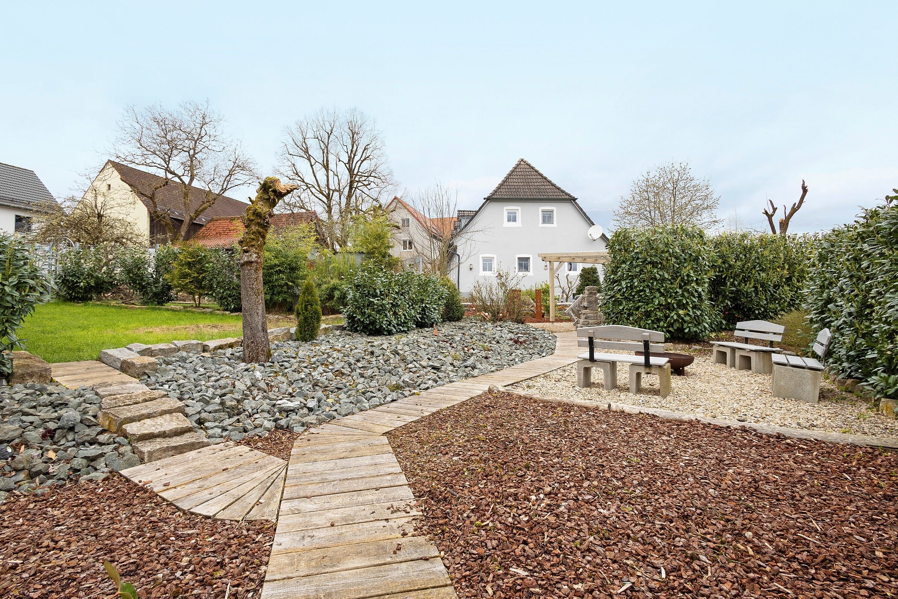 A residential area with a paved pathway, stone steps, and a garden with benches.