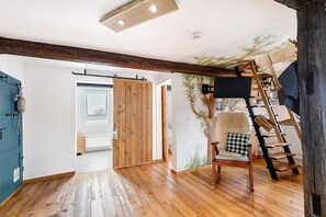 A room with wooden flooring, a wooden chair, a ladder, and a wall mural. - Apartment 'Stub'n Ludwig' with Shared Terrace, Shared Garden and Wi-Fi (Waischenfeld)