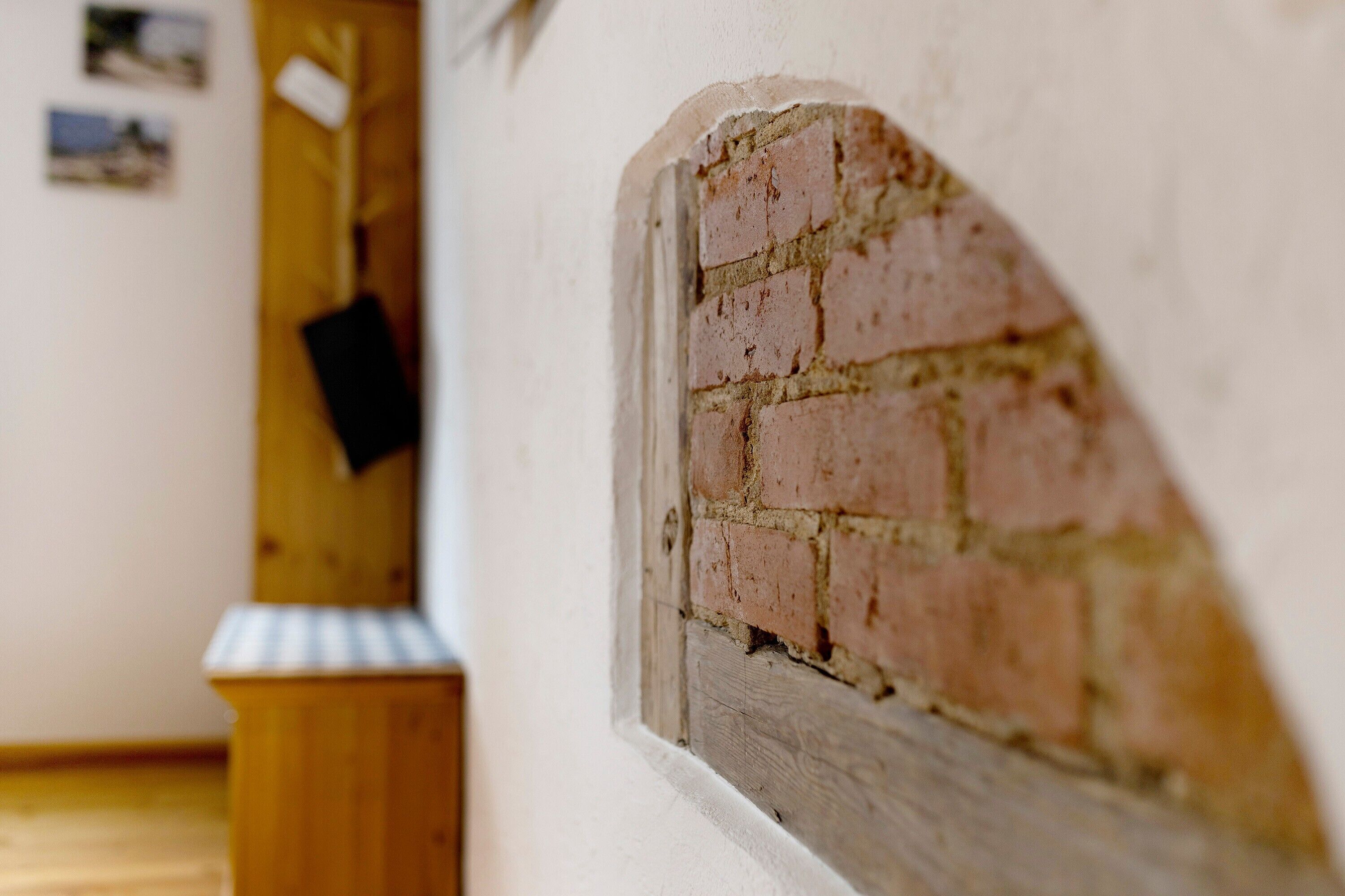 Une pièce avec un mur en briques, une porte en bois et un petit banc en bois.