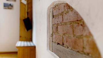 Une pièce avec un mur en briques, une porte en bois et un petit banc en bois.