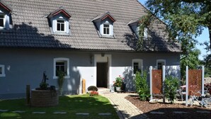 A two-story house with a sloped roof, a front door, and a small front yard with a pathway leading to the entrance. - Apartment 'Stub'n Rettl' with Shared Terrace, Shared Garden and Wi-Fi (Waischenfeld)