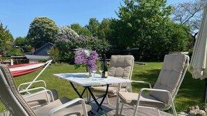 Une terrasse aménagée avec du mobilier d’extérieur, une table et un arrangement floral.