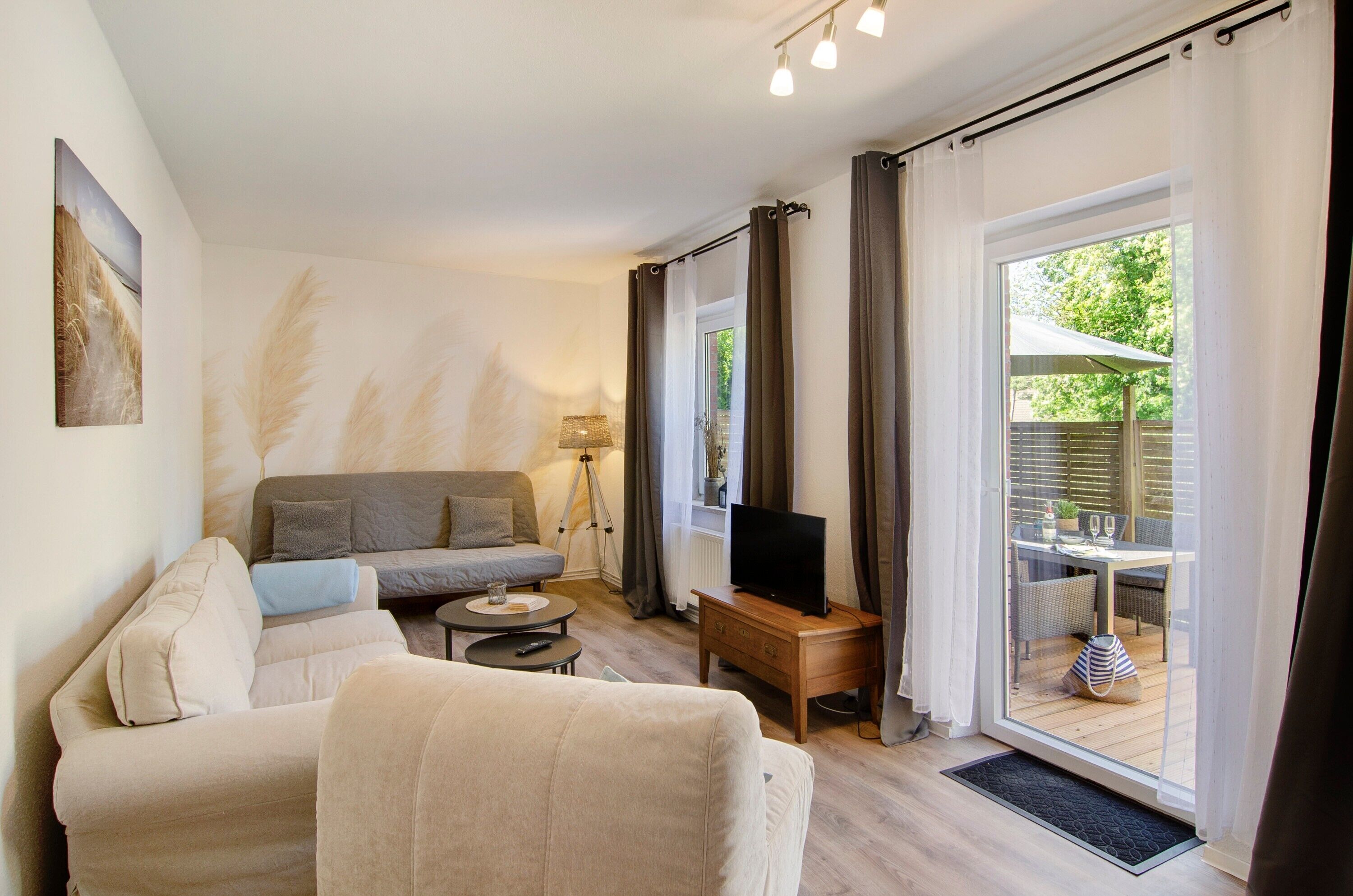 Ein Wohnzimmer mit einer Couch, einem Fernseher, einer Lampe und einem Fenster mit Vorhängen.