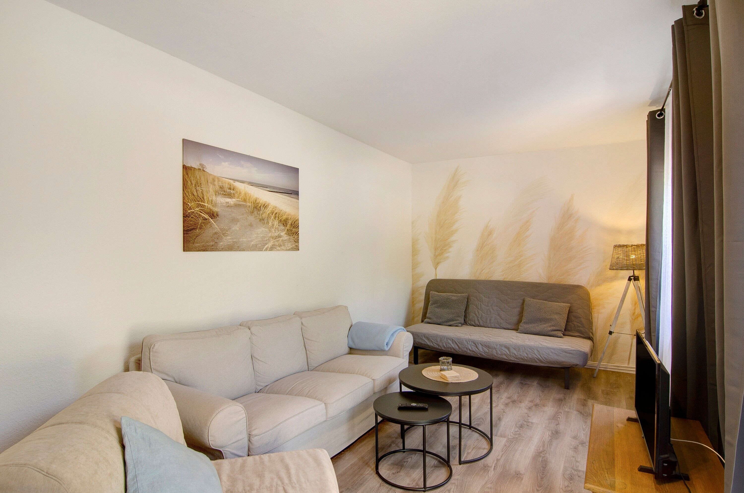 A living room with a sofa, a smaller couch, a coffee table, a lamp, and a TV.