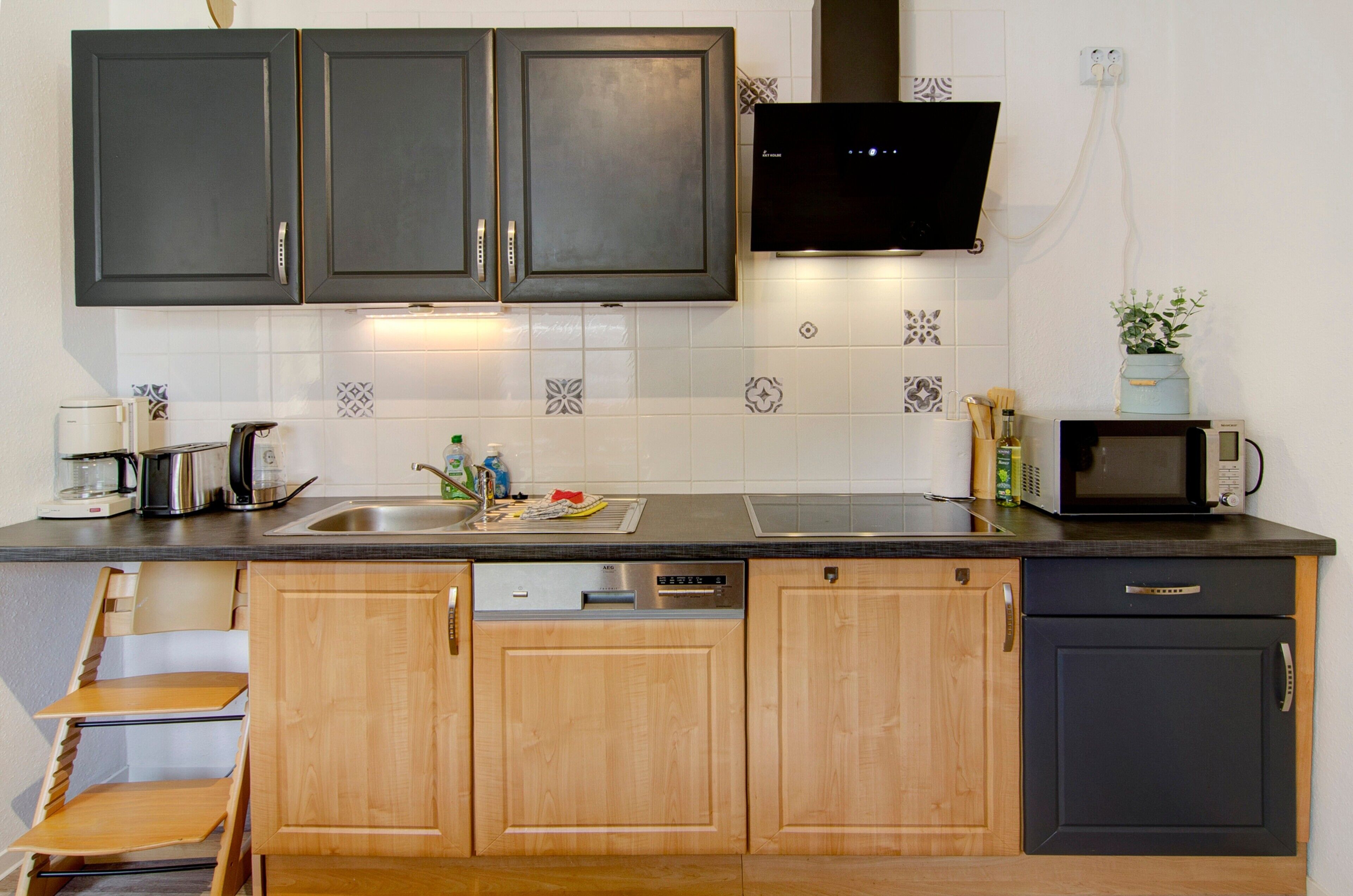 A kitchen with dark cabinets, a microwave, a coffee maker, and a dishwasher.