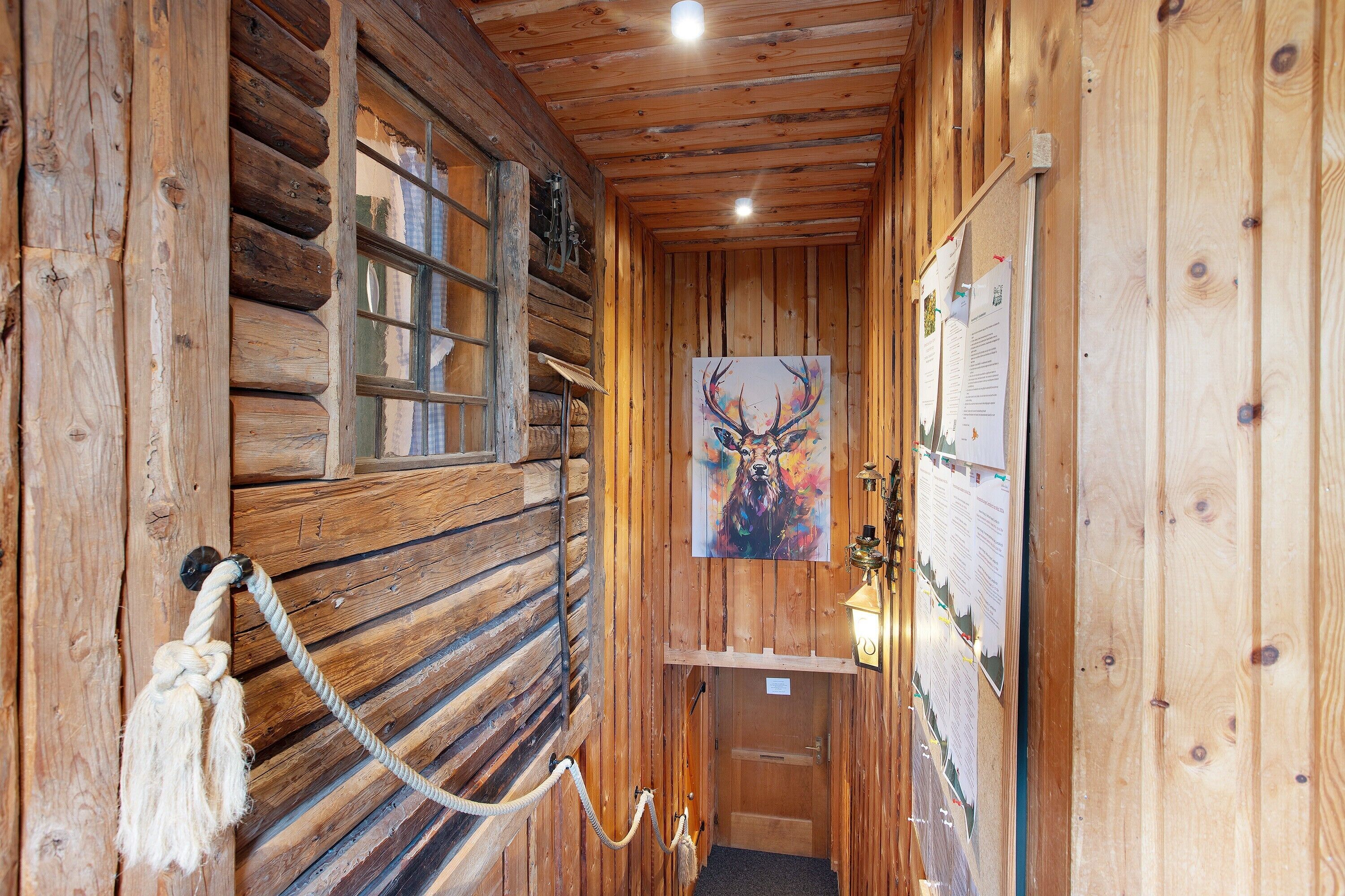Interior de madeira com uma barreira de corda, uma porta e um cartaz de um veado.