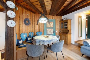 Um interior de madeira com uma mesa redonda, cadeiras em formato de coração azul e um armário.
