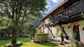 Ein traditionelles Chalet mit Holzbalkon, umgeben von üppigem Grün und einem gepflegten Garten.