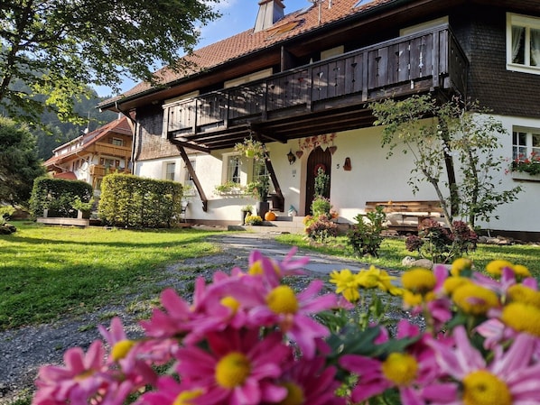 Un chalet traditionnel doté d’un balcon en bois, d’un chemin en pierre et d’un jardin bien entretenu.
