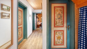 Un couloir avec un plafond en bois, une porte ornée de motifs floraux et un rideau à carreaux.
