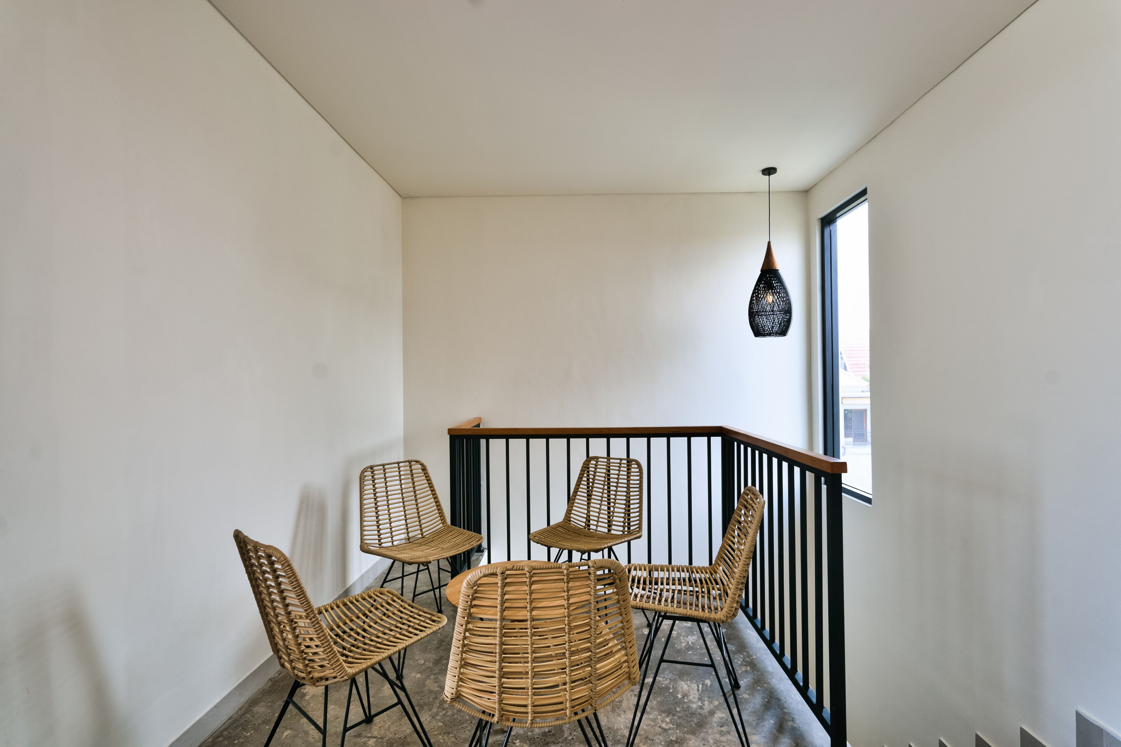 A balcony with wicker chairs and a hanging light fixture.