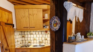 Une cuisine rustique avec des meubles en bois, un pare-feu en carreaux et un sol carrelé.
