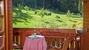 Un balcon en bois avec une table, des chaises et une bouteille d’eau.