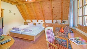 Une pièce en bois avec un lit, un canapé, une petite table et une fenêtre.