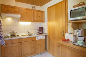 Una cocina con armarios de madera, estufa, cafetera y microondas.